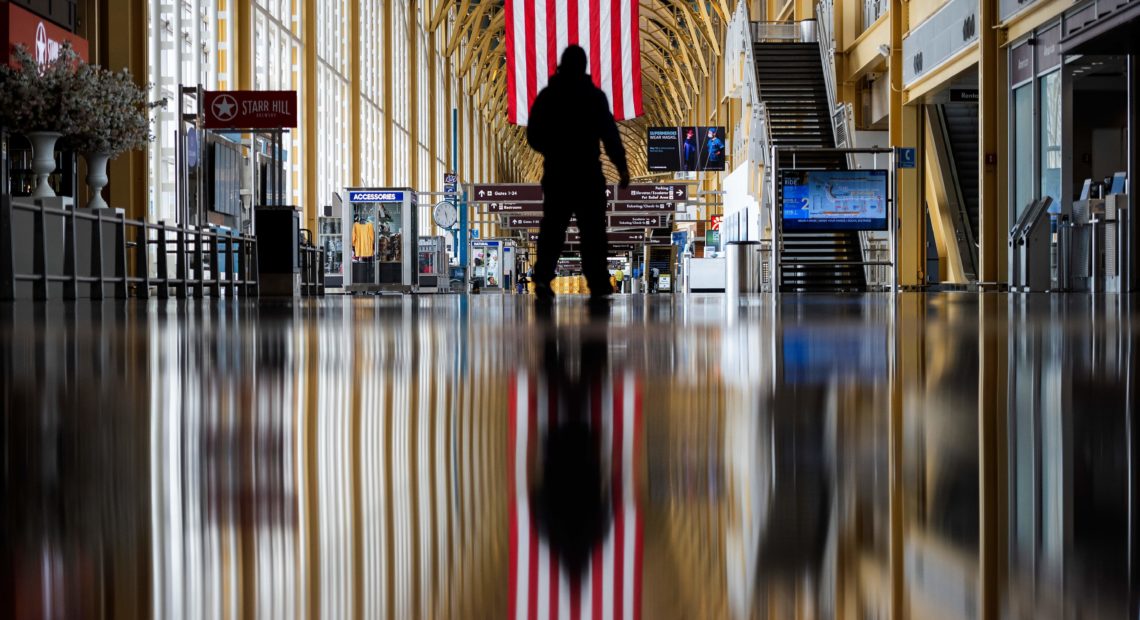 An airport employee walks through Reagan National Airport in Arlington, Va., earlier this year. On Thursday, the Centers for Disease Control and Prevention warned that Americans should refrain from traveling for the upcoming holiday. CREDIT: Andrew Caballero-Reynolds/AFP via Getty Images
