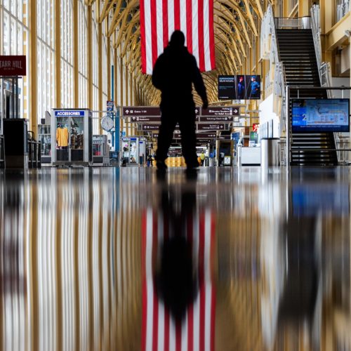 An airport employee walks through Reagan National Airport in Arlington, Va., earlier this year. On Thursday, the Centers for Disease Control and Prevention warned that Americans should refrain from traveling for the upcoming holiday. CREDIT: Andrew Caballero-Reynolds/AFP via Getty Images