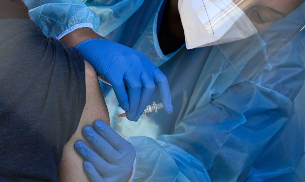 A flu vaccine is administered at a walk-up COVID-19 testing site, in San Fernando, Calif. Emergency use authorization is expected soon for vaccines for COVID-19. Robyn Beck/AFP via Getty Images