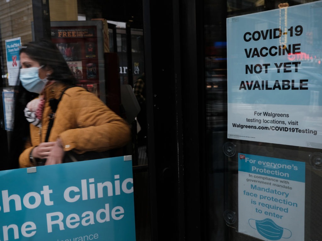 No vaccine available sign - person walking into Walgreens