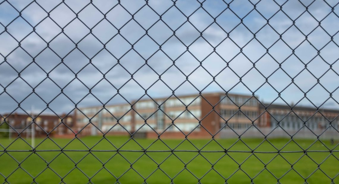 Photo of an empty school looking through a fence