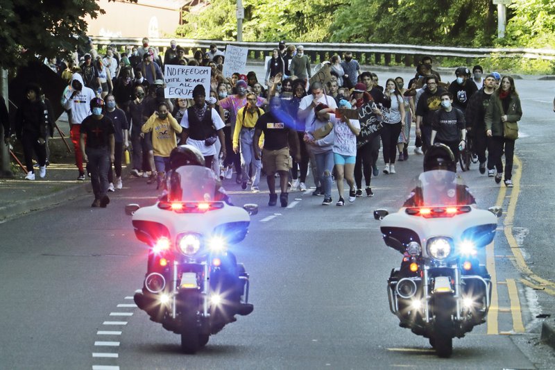 In this June 1, 2020, photo, police on motorcycles escort a protest march in Tacoma against police and the death of George Floyd in Minneapolis days earlier. Washington state lawmakers and activists are setting an ambitious agenda for police reform in the upcoming legislative session. They say they hope to make it easier to decertify officers for misconduct, to bar the use of police dogs to make arrests, and to create an independent statewide agency to investigate police. CREDIT: Photo/Ted S. Warren