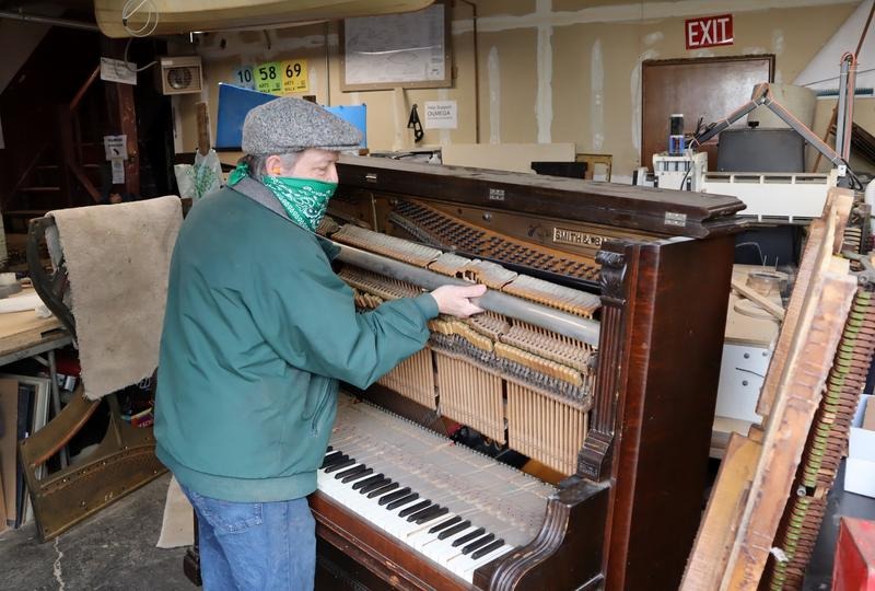 Michael Rohde disassembling a 120-year-old piano to salvage the metal and fine wood for other uses. CREDIT: Tom Banse/N3