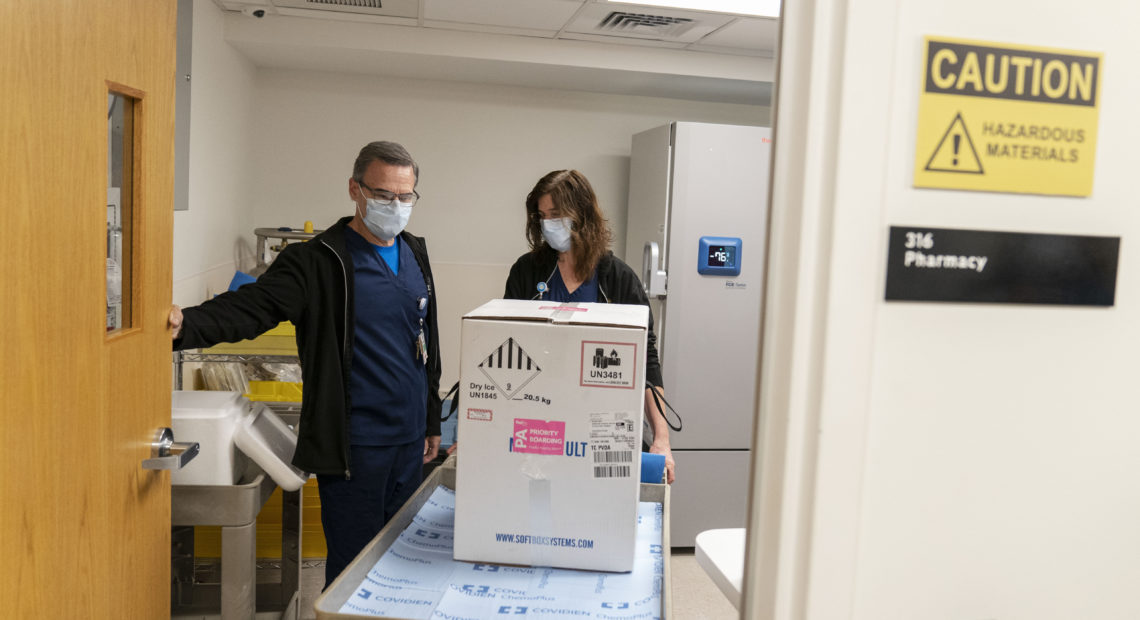 Pharmacists Richard Emery and Karen Nolan wheel a box containing the Pfizer-BioNTech COVID-19 vaccine next to a storage freezer as it arrives at Rhode Island Hospital in Providence, R.I, on Monday. CREDIT: David Goldman/AP