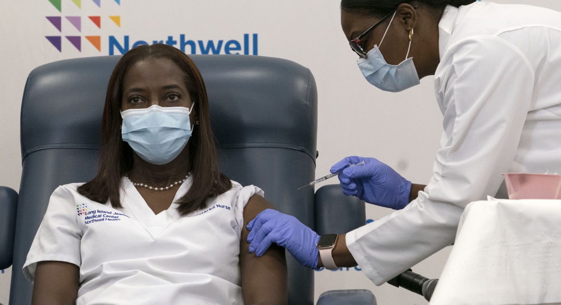 Sandra Lindsay (left) a nurse at Long Island Jewish Medical Center, is inoculated with the Pfizer-BioNTech COVID-19 vaccine by Dr. Michelle Chester on Monday in New York. CREDIT: Mark Lennihan/Pool/AP