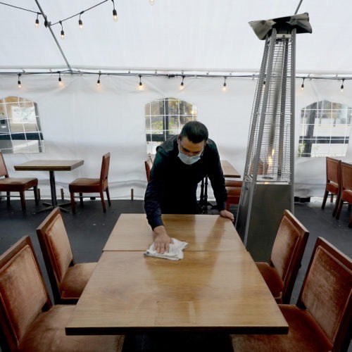 A person cleans a table in an outdoor tented dining area of a restaurant in Sacramento, Calif., on Nov. 19. Job growth slowed sharply in November as relief aid is due to expire at the end of the year. CREDIT: Rich Pedroncelli/AP