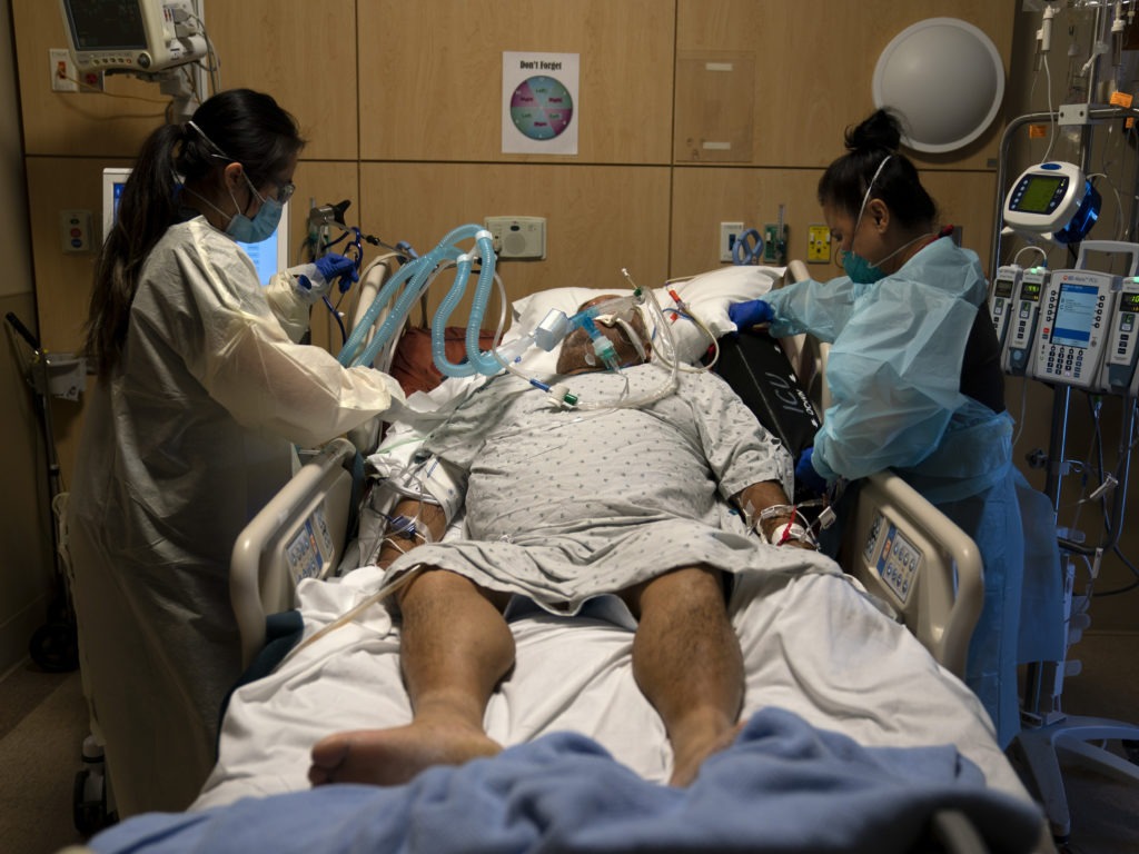 Nurses assist a COVID-19 patient at a Los Angeles hospital last month. The California Department of Health now "strongly recommends" hospitals test all of their health care personnel for the coronavirus each week. CREDIT: Jae C. Hong/AP