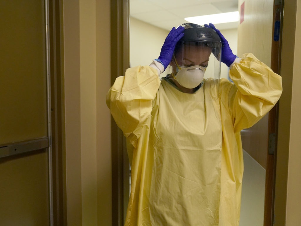 A nurse puts on personal protective equipment last month as she prepares to treat a COVID-19 patient last month at a rural Missouri hospital. CREDIT: Jeff Roberson/AP