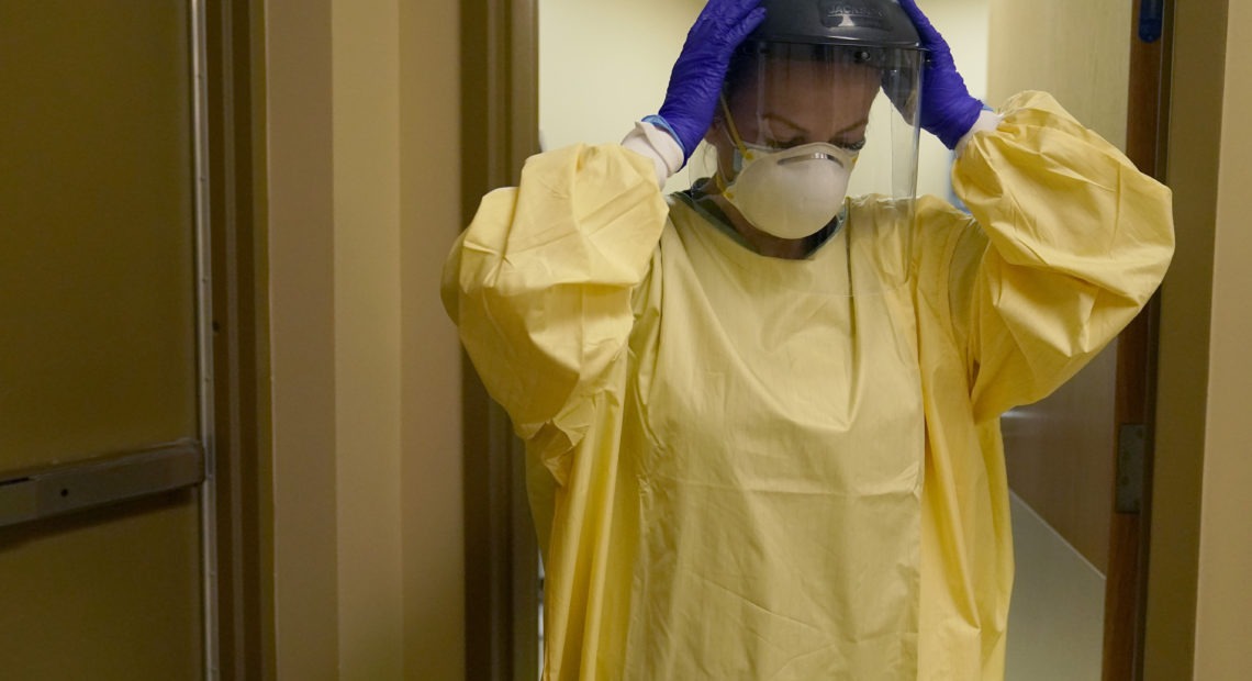 A nurse puts on personal protective equipment last month as she prepares to treat a COVID-19 patient last month at a rural Missouri hospital. CREDIT: Jeff Roberson/AP