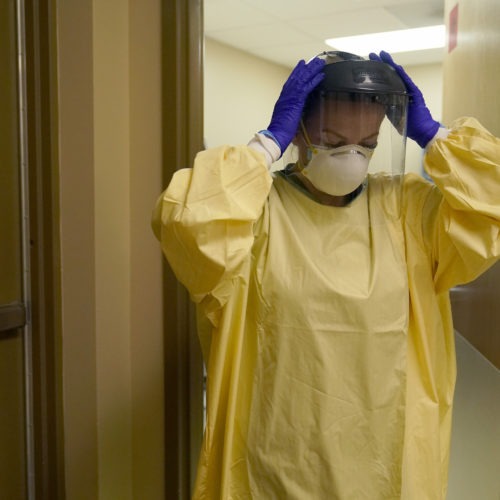 A nurse puts on personal protective equipment last month as she prepares to treat a COVID-19 patient last month at a rural Missouri hospital. CREDIT: Jeff Roberson/AP