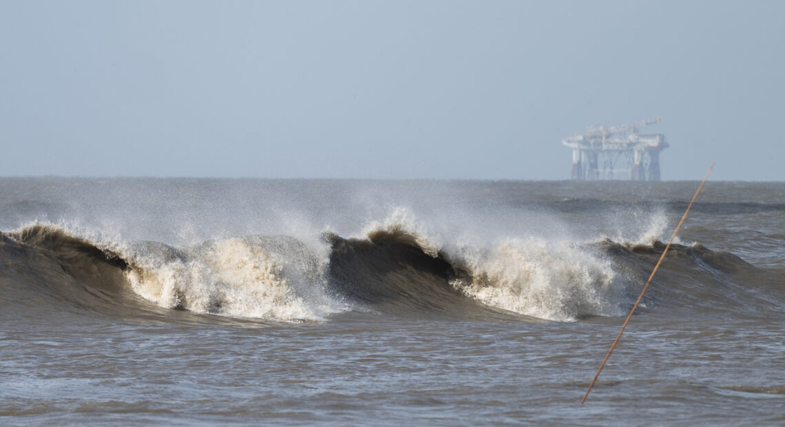 Hurricane Laura sends large waves crashing on a beach in Cameron, La., on Aug. 26 as an offshore oil rig appears in the distance. The most active hurricane season on record was just one of many challenges facing the oil industry this year — aside from the attention-grabbing crisis of the pandemic. CREDIT: Andrew Caballero-Reynolds/AFP via Getty Images