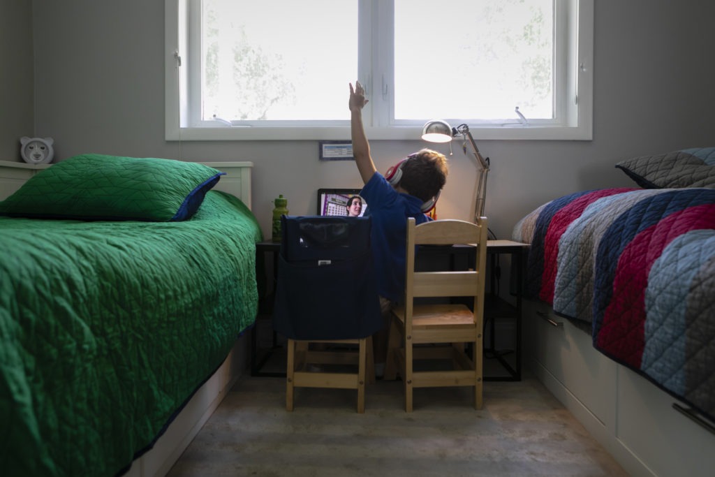 A student raises his hand while attending an online class from home in Miami on Sept. 3. Eva Marie Uzcategui/Bloomberg via Getty Images