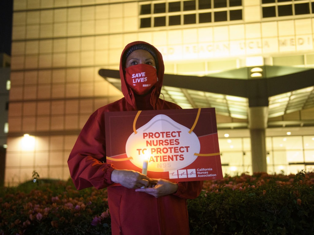 A nurse holds a candle during a vigil in Los Angeles last month for health care workers who have died from COVID-19. The vigil was organized by California Nurses United. Patrick T. Fallon/AFP via Getty Images