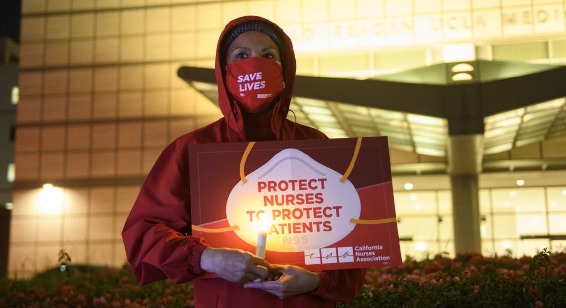 A nurse holds a candle during a vigil in Los Angeles last month for health care workers who have died from COVID-19. The vigil was organized by California Nurses United. Patrick T. Fallon/AFP via Getty Images