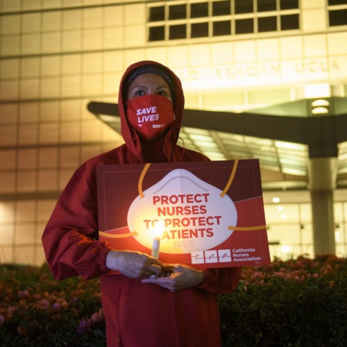 A nurse holds a candle during a vigil in Los Angeles last month for health care workers who have died from COVID-19. The vigil was organized by California Nurses United. Patrick T. Fallon/AFP via Getty Images