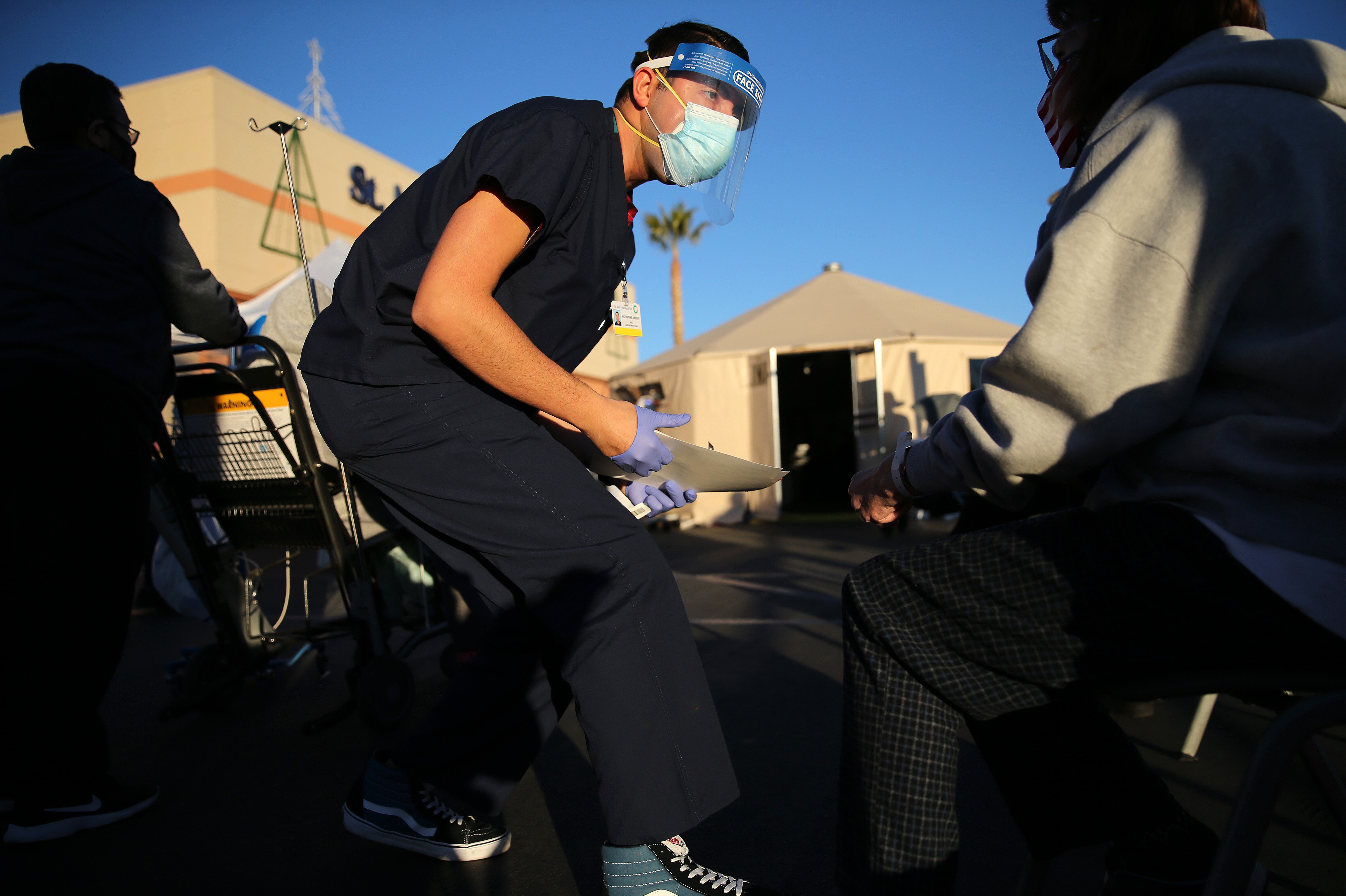 A California National Guard medic prepares to check the vital signs of an incoming patient in front of triage tents outside St. Mary Medical Center last week in Apple Valley amid a surge in COVID-19 patients in Southern California. CREDIT: Mario Tama/Getty Images