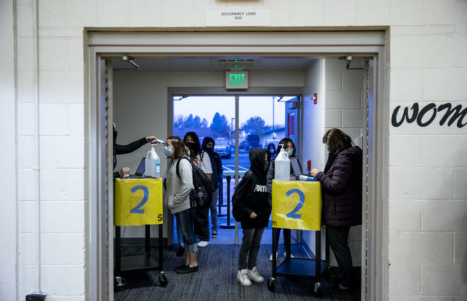 Paraeducators Jerilie Biery, left, and Nadia Ulyanchuk, right, administer required health check-ins with students before school starts at Chief Moses Middle School on Jan. 11, 2020. CREDIT: Dorothy Edwards/Crosscut