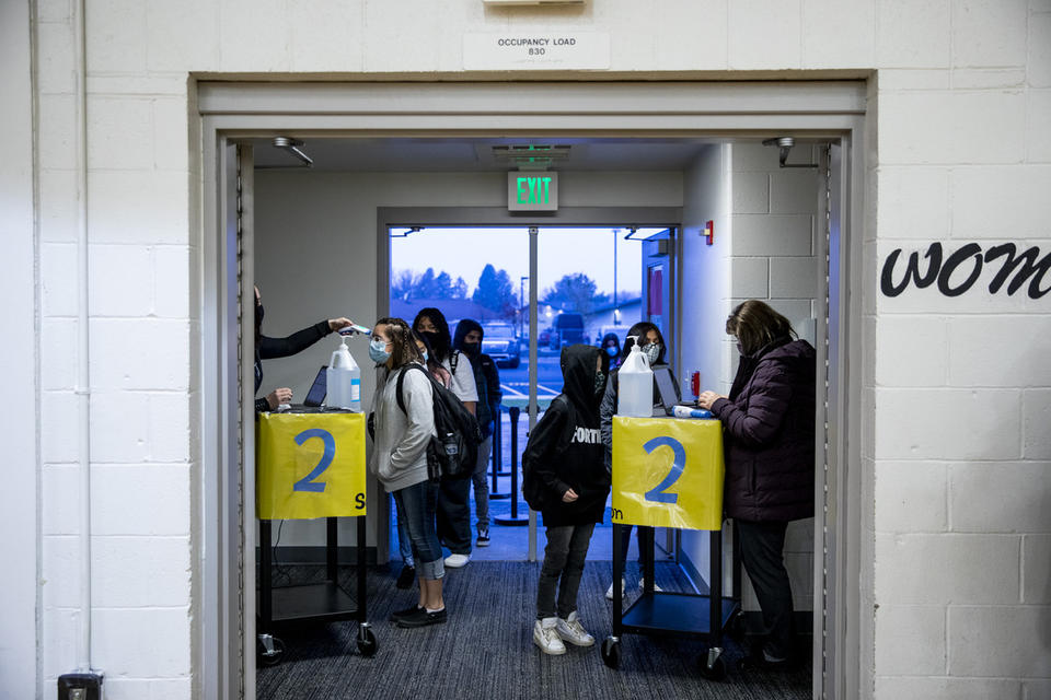 Paraeducators Jerilie Biery, left, and Nadia Ulyanchuk, right, administer required health check-ins with students before school starts at Chief Moses Middle School on Jan. 11, 2020. CREDIT: Dorothy Edwards/Crosscut