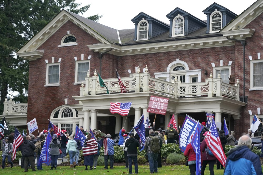Protesters stand outside the Washington Governor's Mansion after getting through a perimeter fence, Wednesday, Jan. 6, 2021, at the Capitol in Olympia following a protest against the counting of electoral votes in Washington, DC, affirming President-elect Joe Biden's victory. The area was eventually cleared by police. CREDIT: Ted S. Warren/AP
