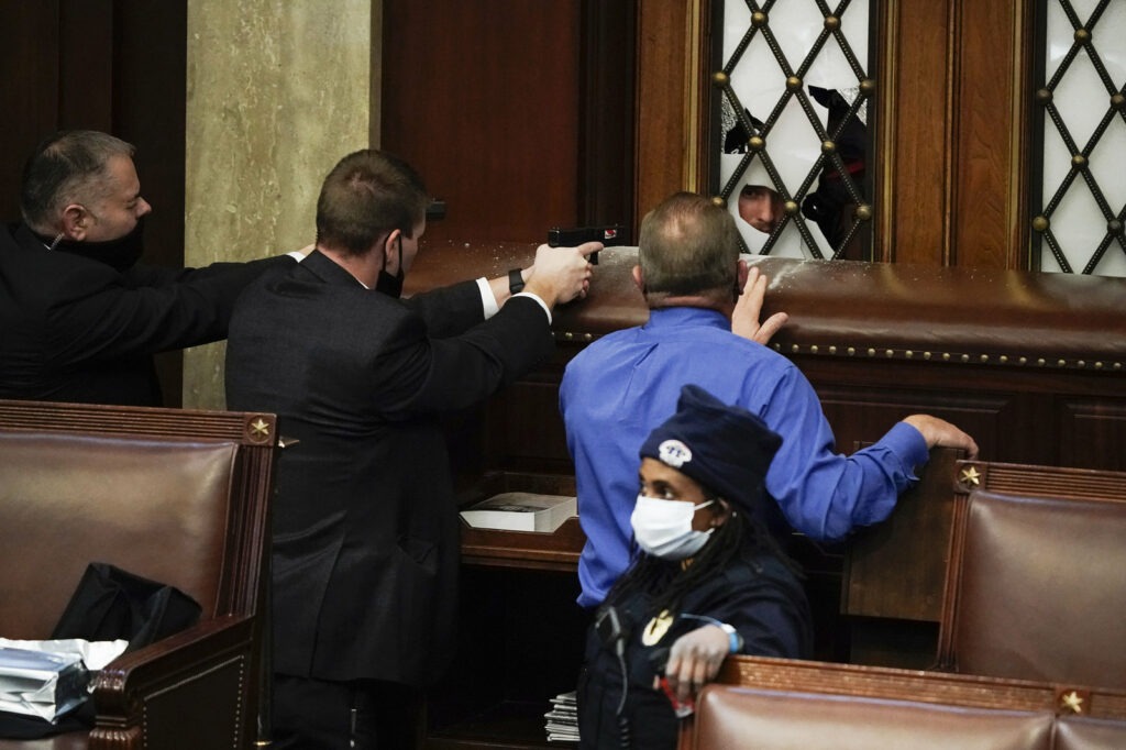 Police with guns drawn face off with protesters trying to break into the House chamber at the Capitol. J. Scott Applewhite/AP