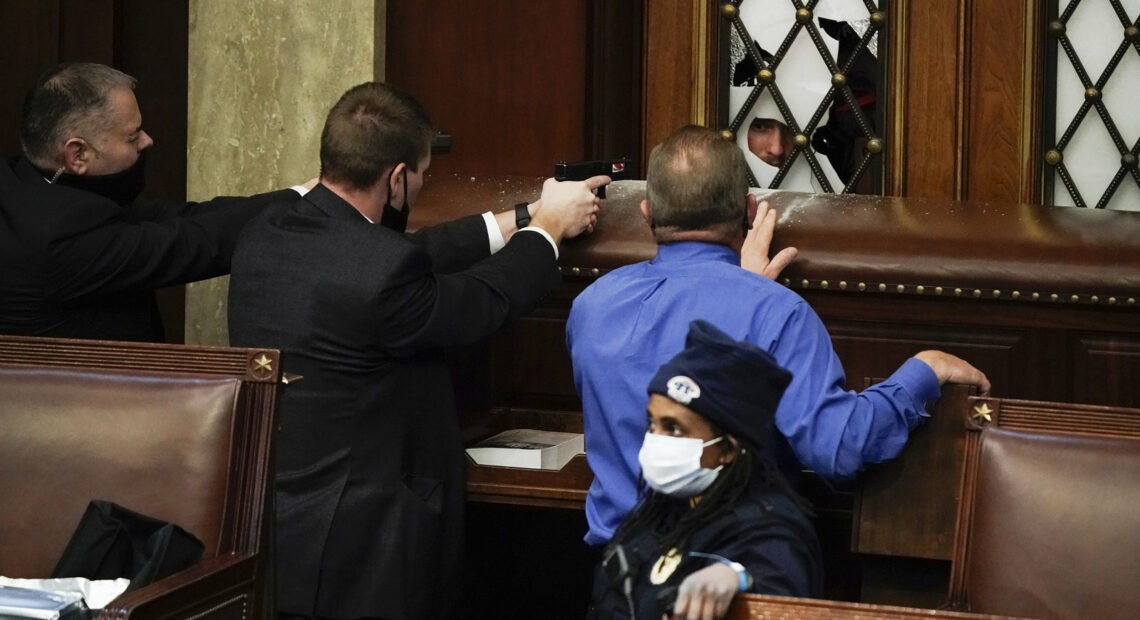 Police with guns drawn face off with protesters trying to break into the House chamber at the Capitol. J. Scott Applewhite/AP