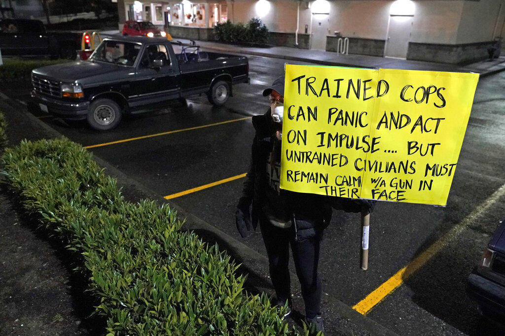 A person holds a sign during a protest against police brutality, late Sunday, Jan. 24, 2021, in downtown Tacoma, Wash., south of Seattle. The protest came a day after at least two people were injured when a Tacoma Police officer responding to a report of a street race drove his car through a crowd of pedestrians that had gathered around him. Several people were knocked to the ground and at least one person was run over. CREDIT: Ted S. Warren/AP