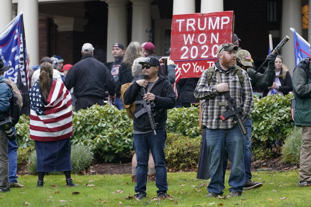 Supporters of President Trump, including those with guns and a bat, stand outside the Governor's Mansion after breaching a perimeter fence, Wednesday, Jan. 6, 2021, at the Capitol in Olympia, Wash. CREDIT: Ted S. Warren/AP