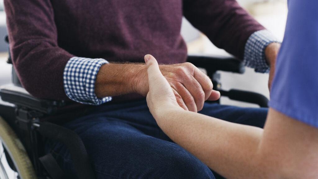 Cropped shot of a nurse holding hands with a senior man in a wheelchair