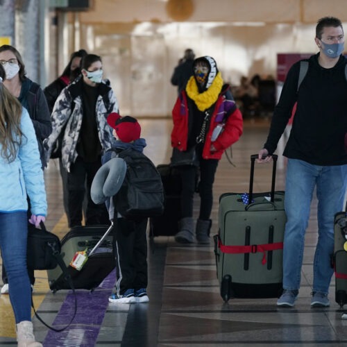 Travelers wear face masks in the main terminal of Denver International Airport on Dec. 31, 2020. Starting Feb. 1, travelers will be required to wear face masks on nearly all forms of public transportation. CREDIT: David Zalubowski/AP