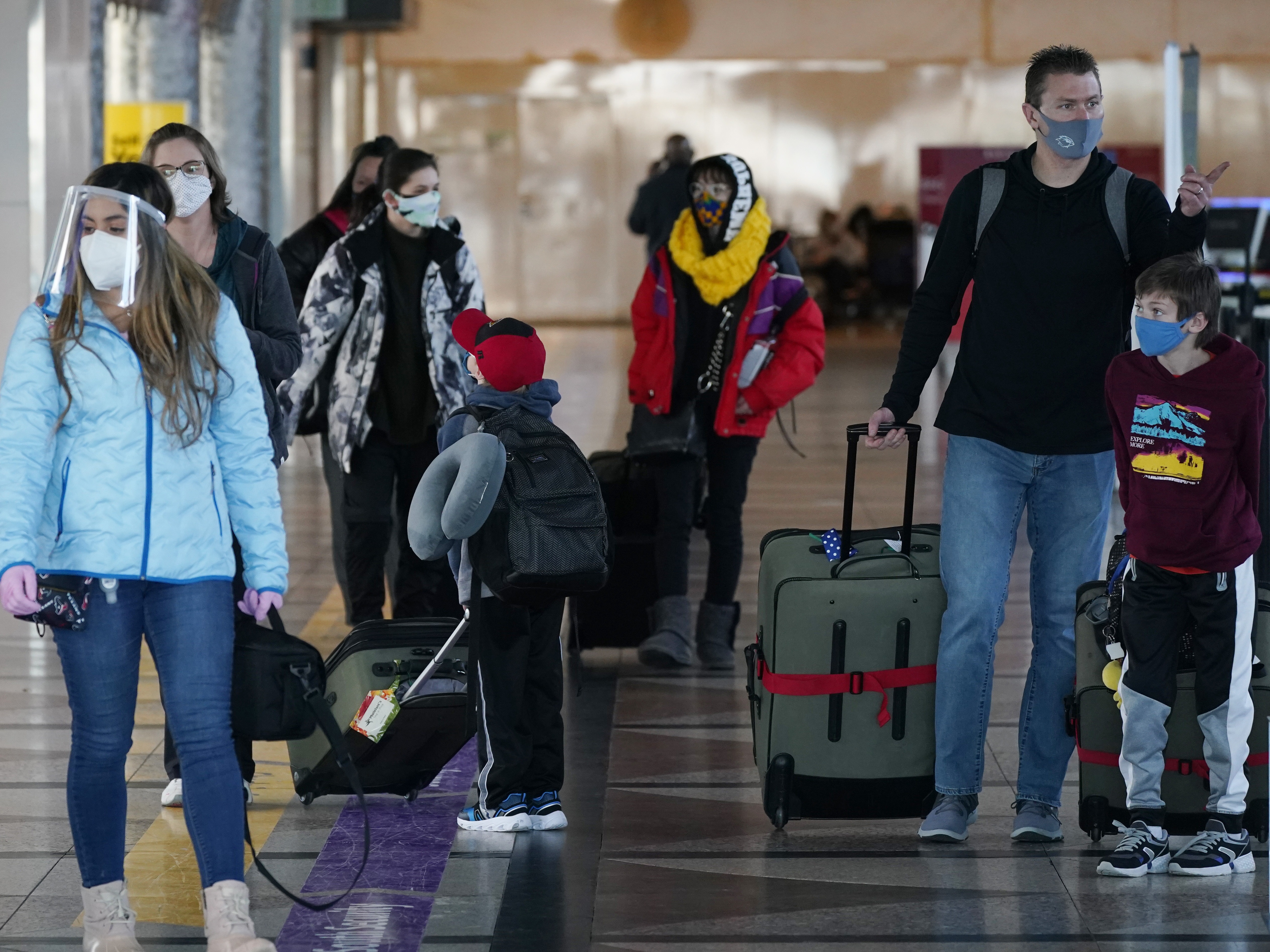 Travelers wear face masks in the main terminal of Denver International Airport on Dec. 31, 2020. Starting Feb. 1, travelers will be required to wear face masks on nearly all forms of public transportation. CREDIT: David Zalubowski/AP