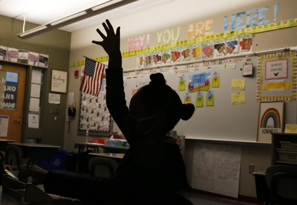 A first-grader raises her hand at Mary L. Fonseca Elementary School in Fall River, Mass., in November. Jessica Rinaldi/Boston Globe via Getty Images