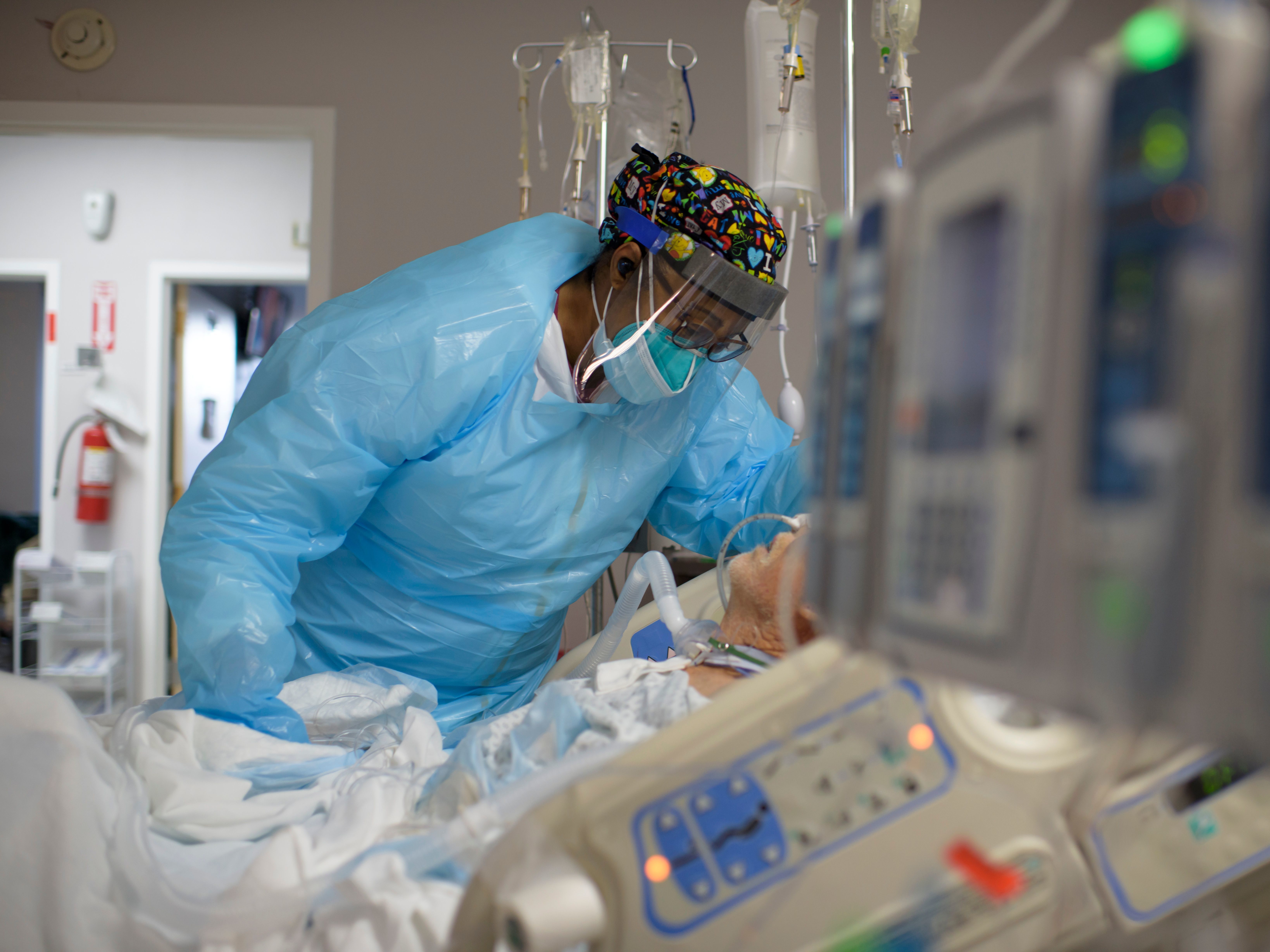 Health care worker Demetra Ransom comforts a patient in the COVID-19 ward at United Memorial Medical Center in Houston last month. The U.S. has since surpassed 20 million confirmed coronavirus cases. CREDIT: Mark Felix/AFP via Getty Images