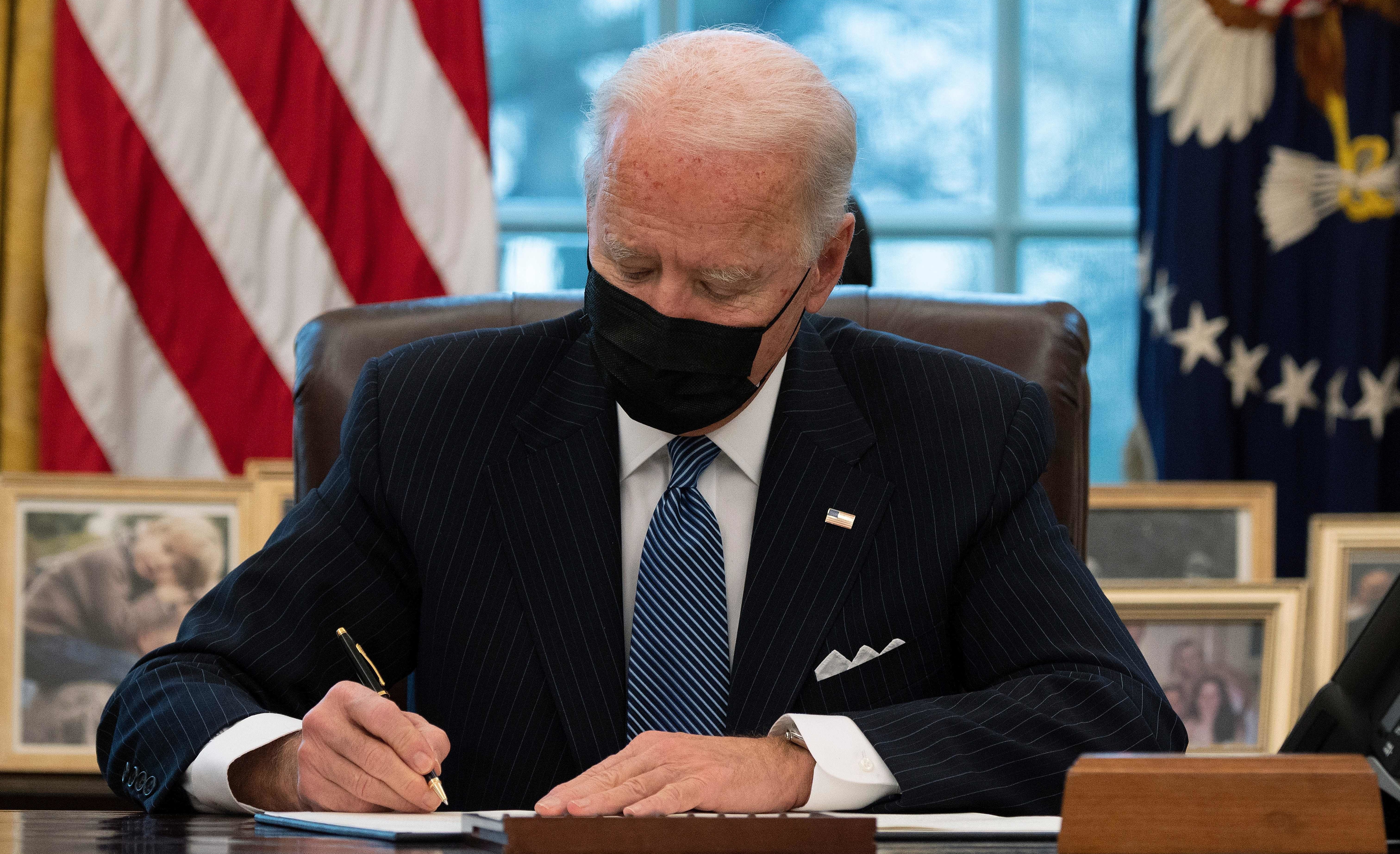 President Biden signs an executive order Monday reversing a Trump-era ban on transgender people serving in the military. Jim Watson/AFP via Getty Images