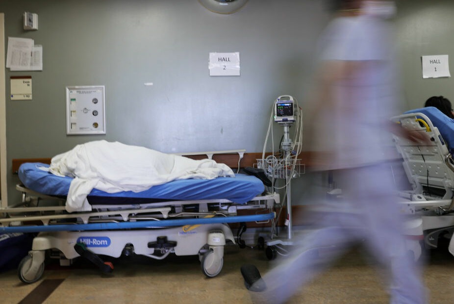 A patient lies on a stretcher in the hallway of the overloaded emergency room at Providence St. Mary Medical Center amid a surge in COVID-19 patients in Southern California in late December. Average new daily infections are now going down in California and much of the country. CREDIT: Mario Tama/Getty Images