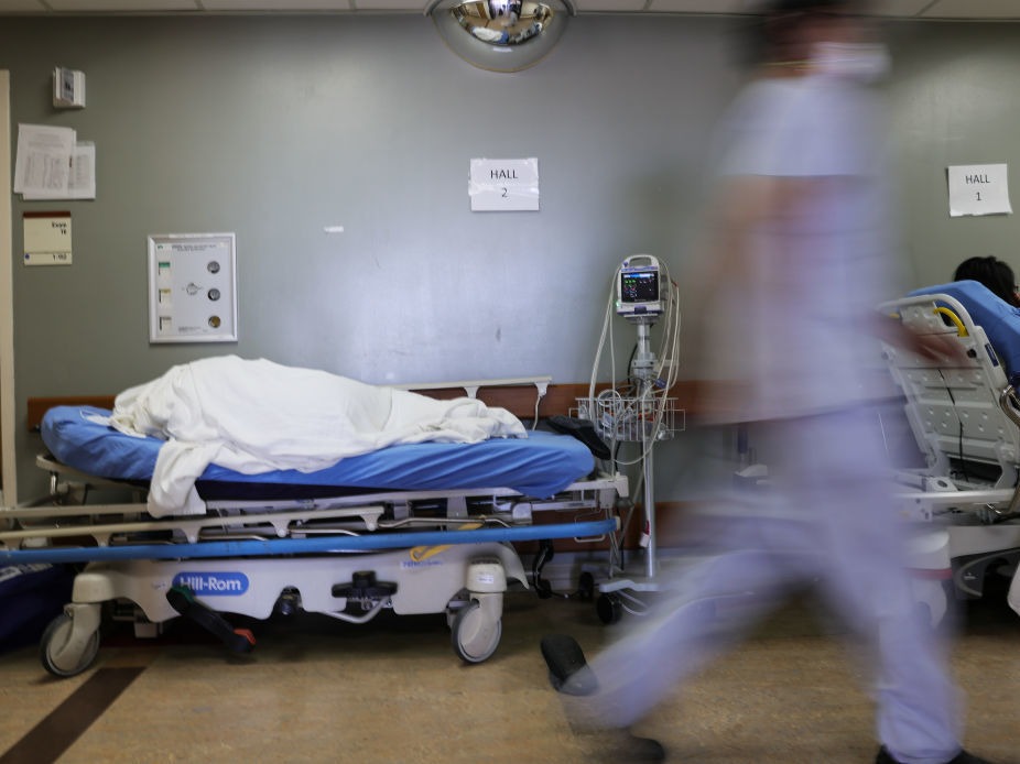 A patient lies on a stretcher in the hallway of the overloaded emergency room at Providence St. Mary Medical Center amid a surge in COVID-19 patients in Southern California in late December. Average new daily infections are now going down in California and much of the country. CREDIT: Mario Tama/Getty Images