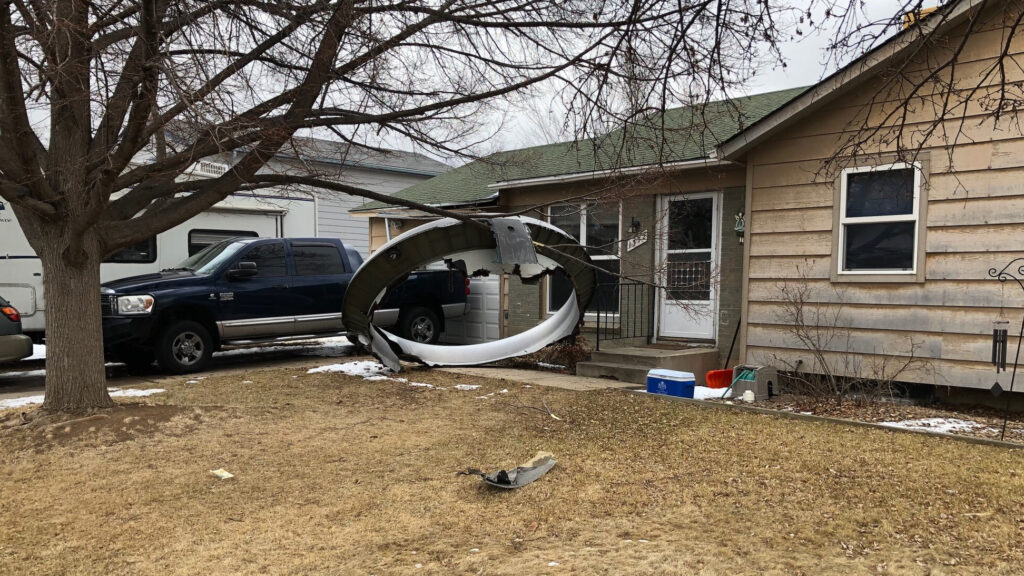 Debris is scattered in the front yard of a house in Broomfield, Colo., Saturday. A commercial airliner dropped debris in Colorado neighborhoods during an emergency landing Saturday. Broomfield Police Department via AP