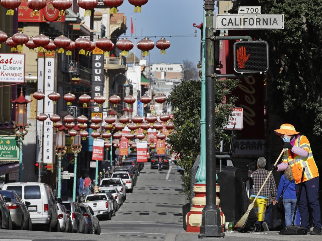 In this Jan. 31, 2020, file photo, a masked worker cleans a street in the Chinatown district in San Francisco. Police and volunteers have increased their street presence after a series of violent attacks against older Asian residents in Bay Area cities stoked fear and subdued the celebratory mood leading up to the Lunar New Year. (AP Photo/Ben Margot, File) Ben Margot/AP