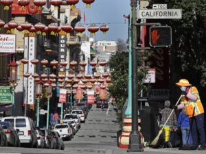 In this Jan. 31, 2020, file photo, a masked worker cleans a street in the Chinatown district in San Francisco. Police and volunteers have increased their street presence after a series of violent attacks against older Asian residents in Bay Area cities stoked fear and subdued the celebratory mood leading up to the Lunar New Year. (AP Photo/Ben Margot, File) Ben Margot/AP