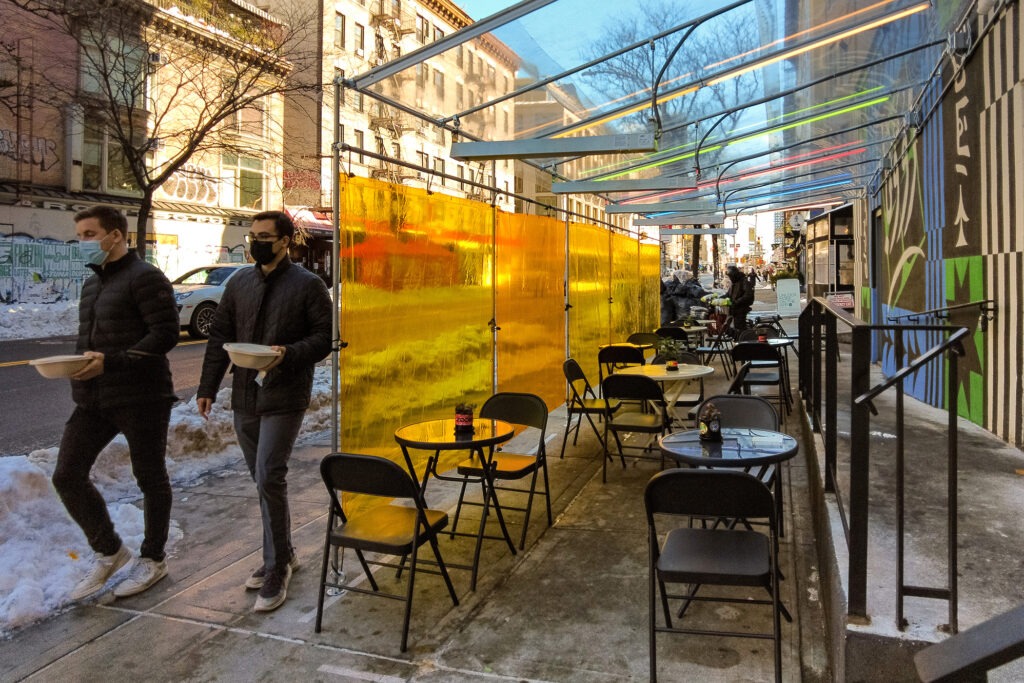 pedestrians walk pas an outdoor dining outside patio