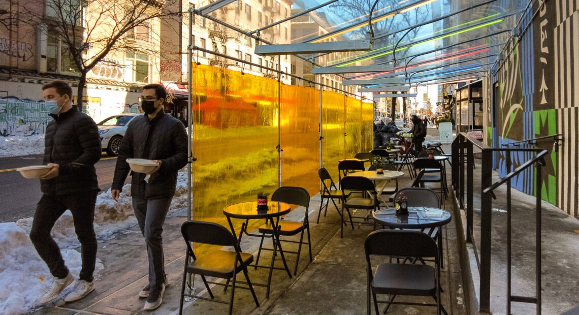 pedestrians walk pas an outdoor dining outside patio