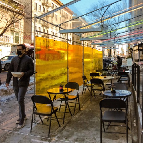 pedestrians walk pas an outdoor dining outside patio