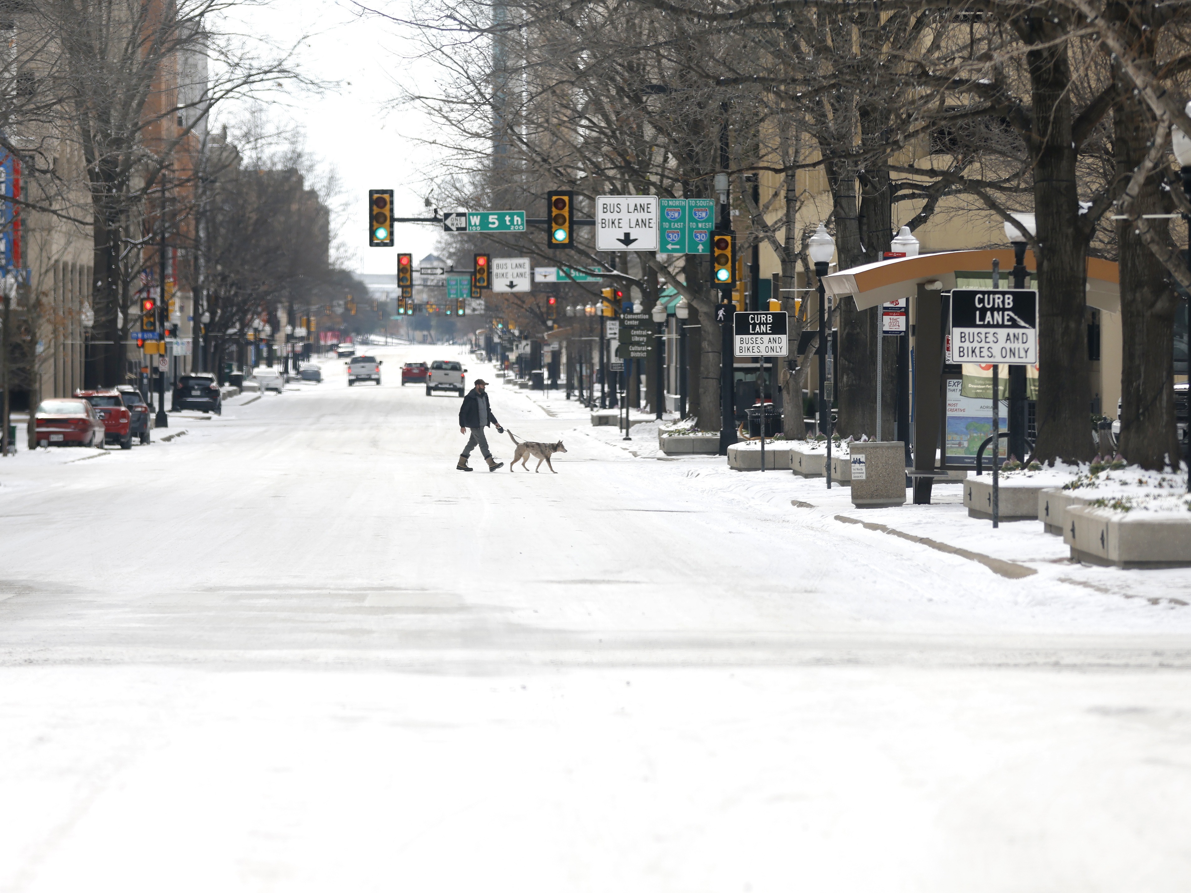 A man walks his dog downtown after a snowstorm this week in Fort Worth, Texas. The winter storm has brought historic cold weather and power outages to more than two dozen states, with a mix of freezing temperatures and precipitation. Ron Jenkins/Getty Images