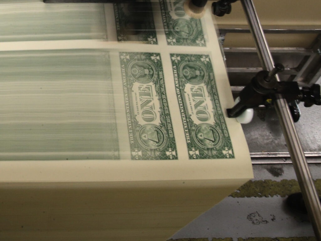 Sheets of one-dollar bills run through the printing press at the Bureau of Engraving and Printing in 2015 in Washington, D.C. Congressional forecasters projected the federal deficit this fiscal year will hit its highest since World War II. Mark Wilson/Getty Images