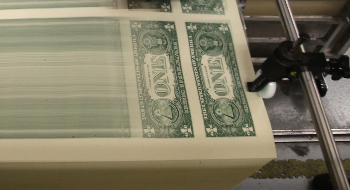 Sheets of one-dollar bills run through the printing press at the Bureau of Engraving and Printing in 2015 in Washington, D.C. Congressional forecasters projected the federal deficit this fiscal year will hit its highest since World War II. Mark Wilson/Getty Images