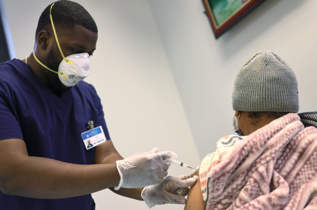 Kurtis Smith gives the Moderna coronavirus vaccine to a resident at Red Hook Neighborhood Senior Center in Brooklyn, N.Y., on Monday. CREDIT: Michael M. Santiago/Getty Images