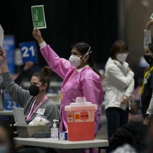 Dr. Preetma Kooner, left, and registered nurse Emily Beedle, right, talk on March 13, 2021 as the first patients arrive at the mass vaccination site at Lumen Field Event Center in Seattle. More people will be eligible for the vaccine as of March 31. CREDIT: Megan Farmer/KUOW