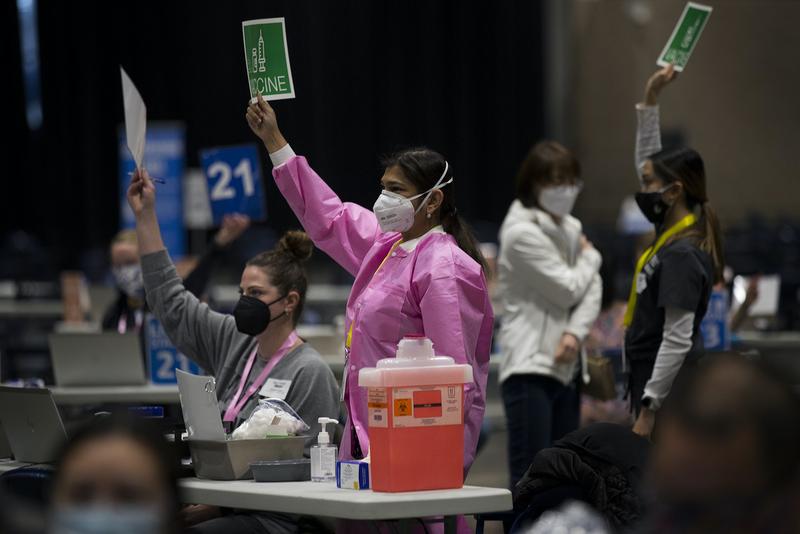 Dr. Preetma Kooner, left, and registered nurse Emily Beedle, right, talk on March 13, 2021 as the first patients arrive at the mass vaccination site at Lumen Field Event Center in Seattle. More people will be eligible for the vaccine as of March 31. CREDIT: Megan Farmer/KUOW