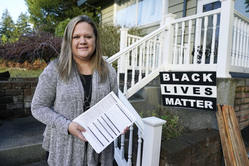 File photo, Dec. 2020. State Rep. Tarra Simmons, D-Bremerton, holds blank voter registration forms as she poses for a photo at her home in Bremerton, Wash. Simmons was incarcerated herself before being released and becoming a lawyer, and then winning a state House seat in 2020. CREDIT: Ted S. Warren/AP