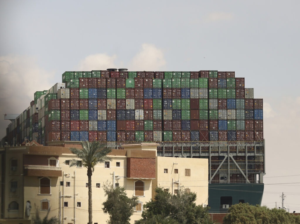 The Panama-flagged Ever Given is seen wedged across the Suez Canal on Friday. Tugboats, dredgers and even land-based, earth-moving equipment have been pressed into service to try to free the 1,300-foot container ship. CREDIT: Mohamed Elshahed/AP