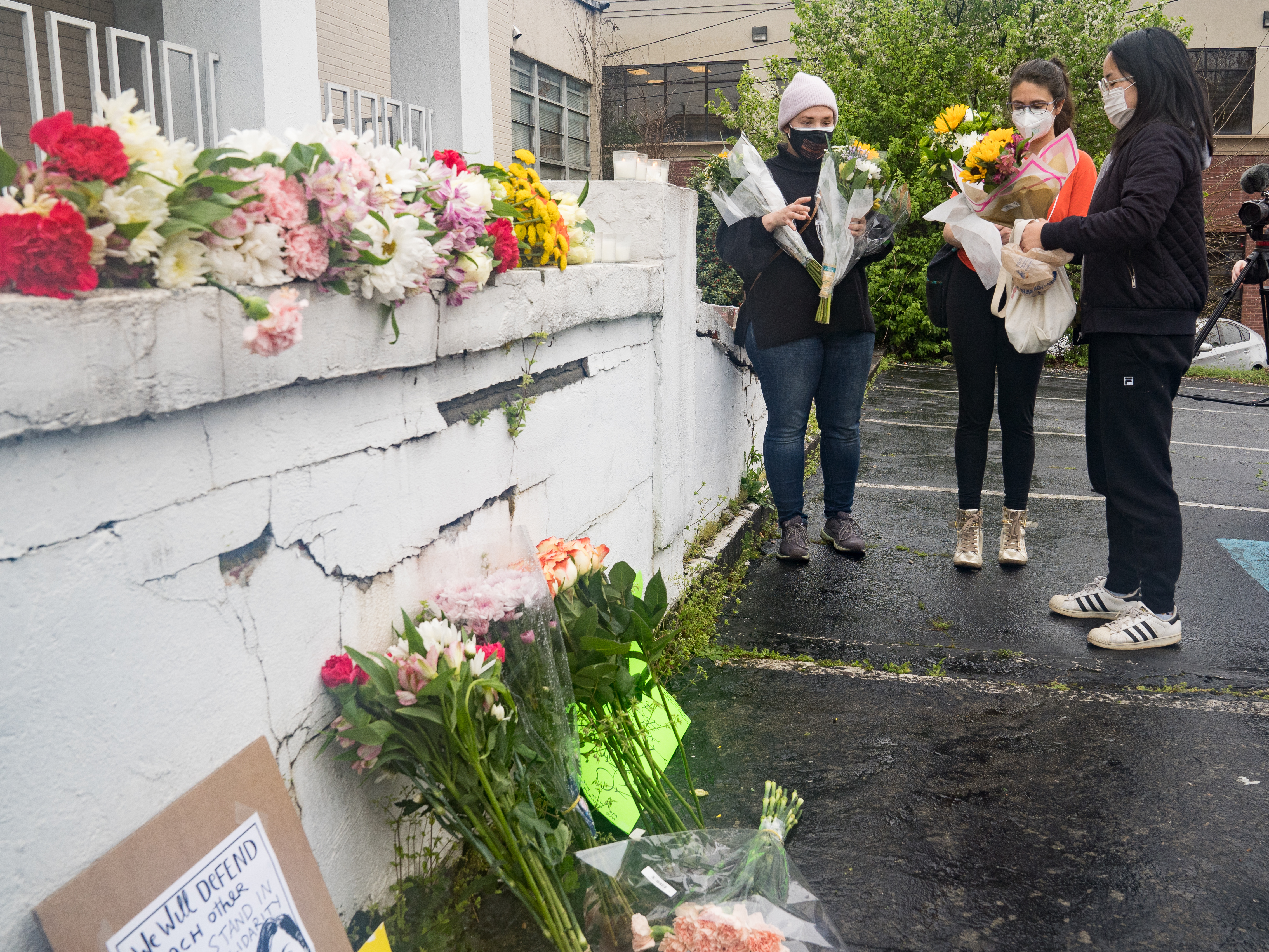 Mourners visit and leave flowers on Wednesday at the site of two shootings at spas across the street from one another in Atlanta. CREDIT: Megan Varner/Getty Images